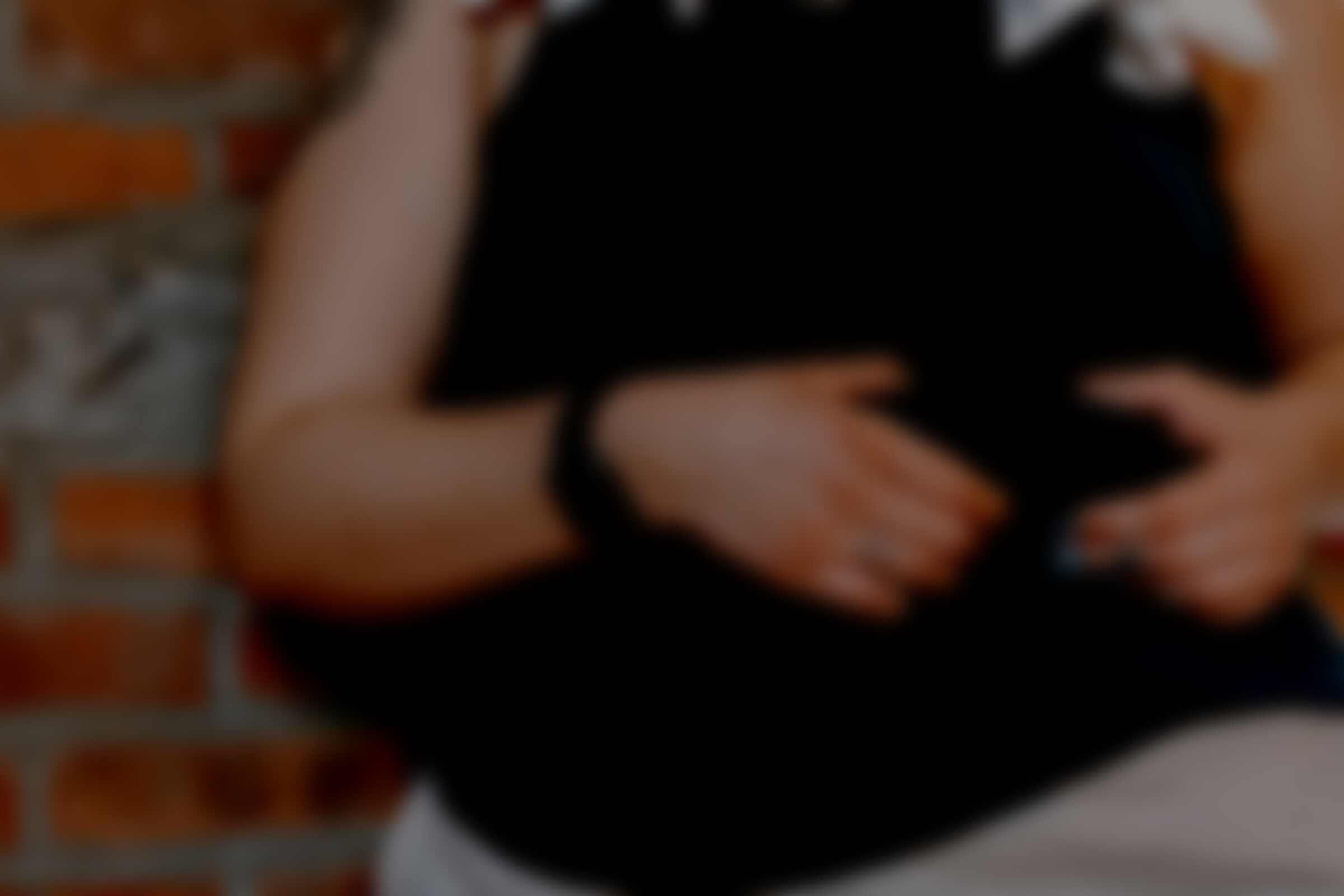 Tattooed woman showing overweight belly near brick wall